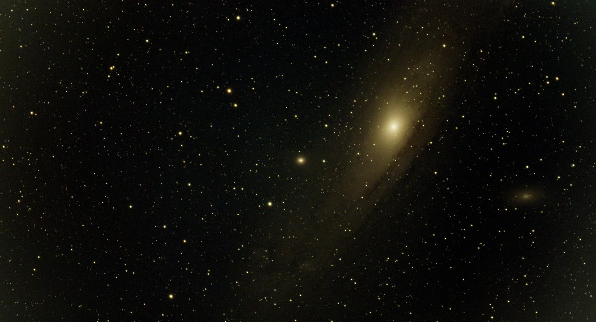 An inclined spiral galaxy with a bright golden center in a dense star field