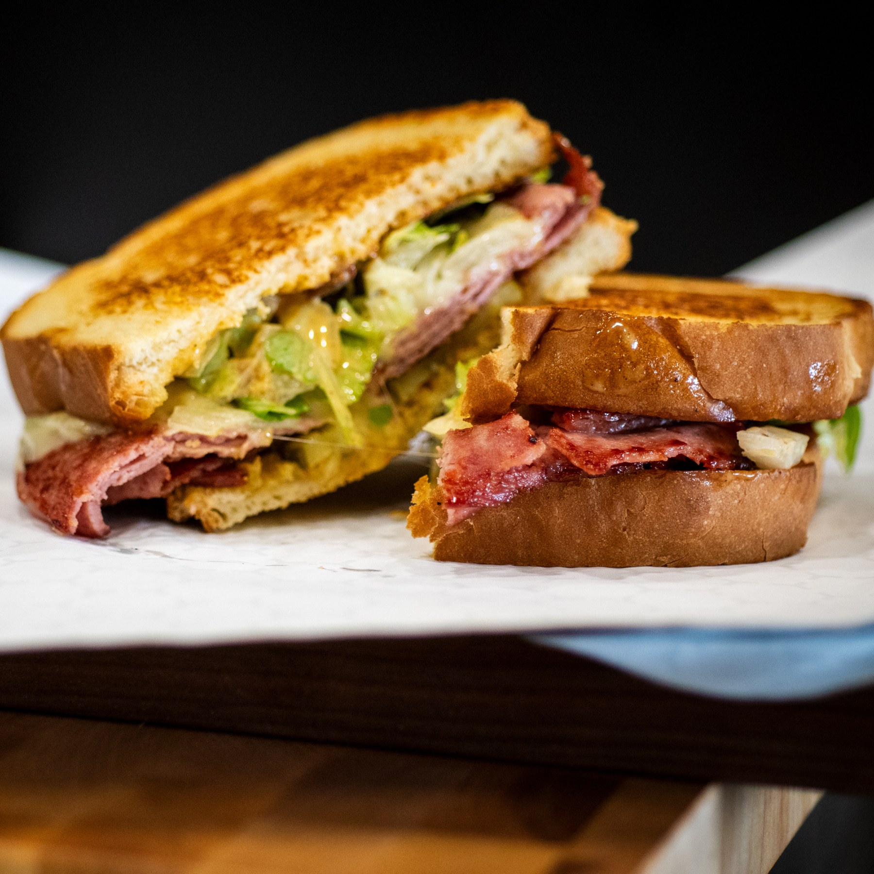 Two halves of a toasted sandwich with meat, lettuce, and melted cheese